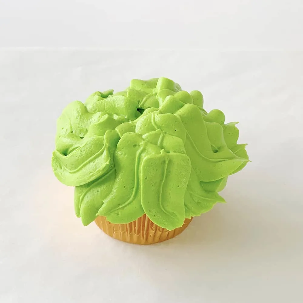 green vanilla buttercream frosting on cupcake with jungle leaves