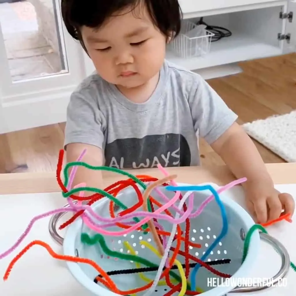 Pipe cleaners in a colander for toddler fine motor skills 