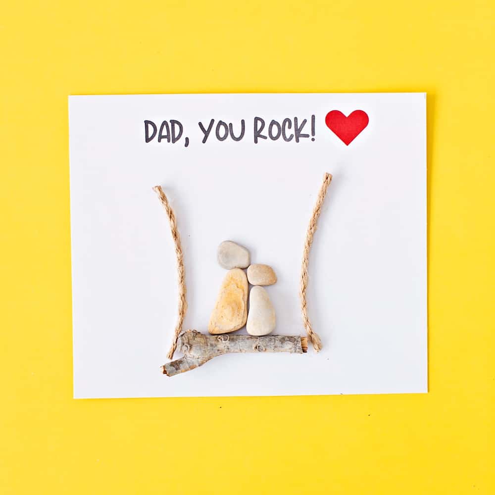 pebble rock art on yellow background for father's day that says dad, you rock