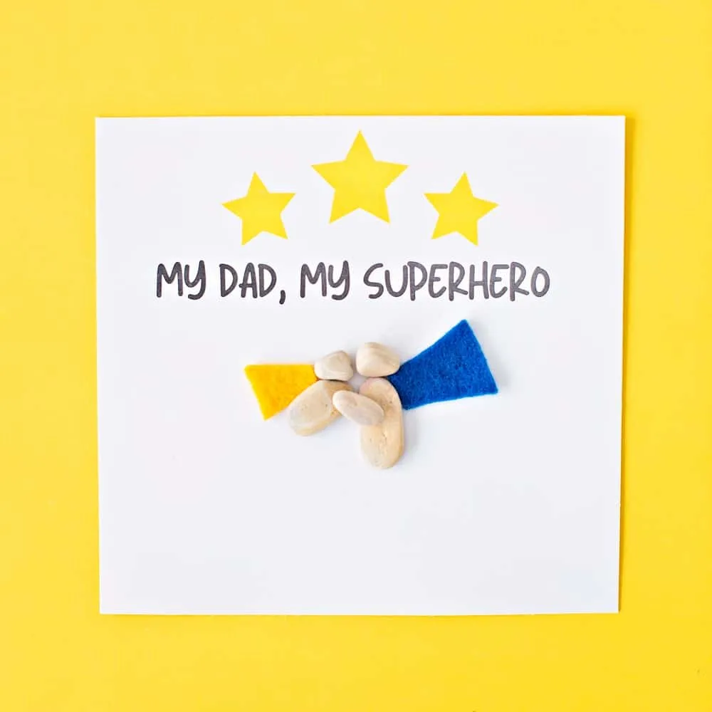 pebble rock art on yellow background for father's day that says My dad, my superhero