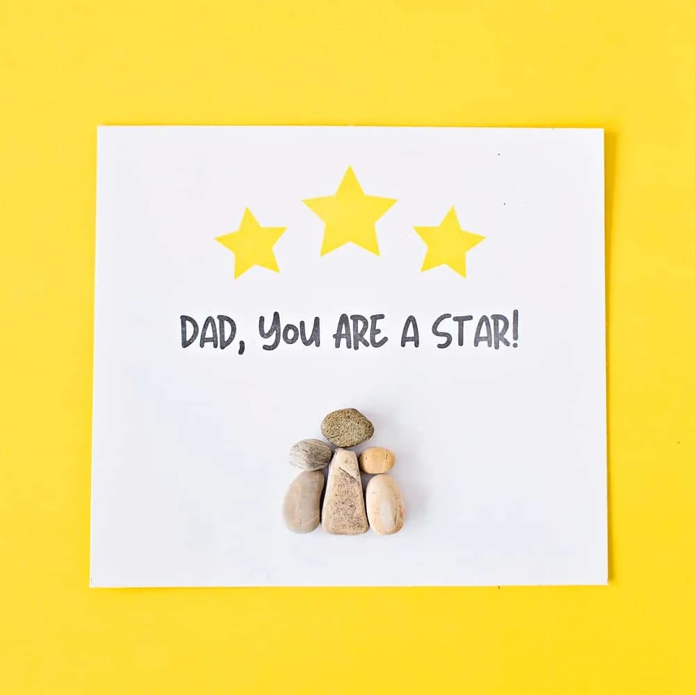 pebble rock art on yellow background for father's day that says dad you are a star