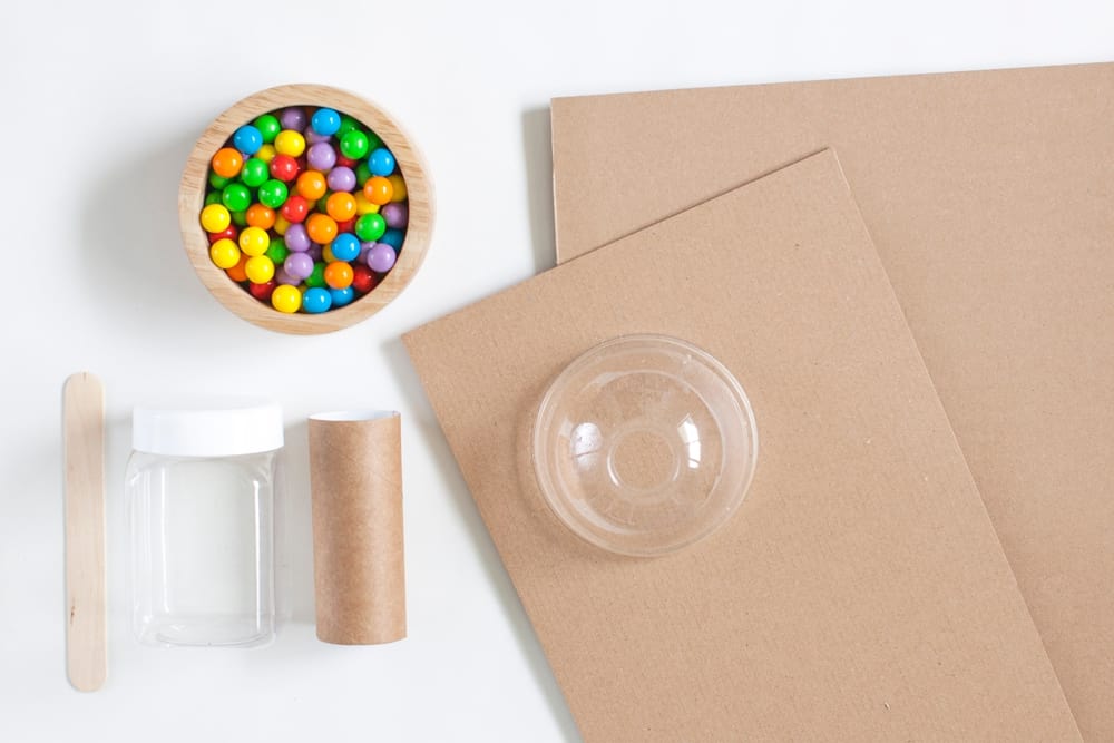 materials laid out to make a gumball machine showing cardboard, paper tube and candy