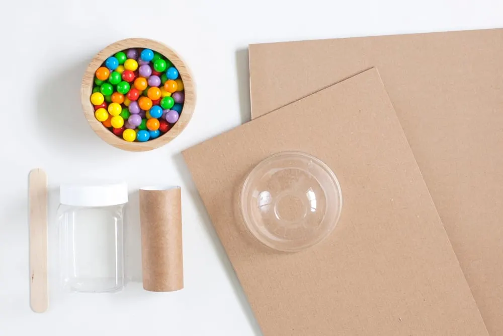 materials laid out to make a gumball machine showing cardboard, paper tube and candy