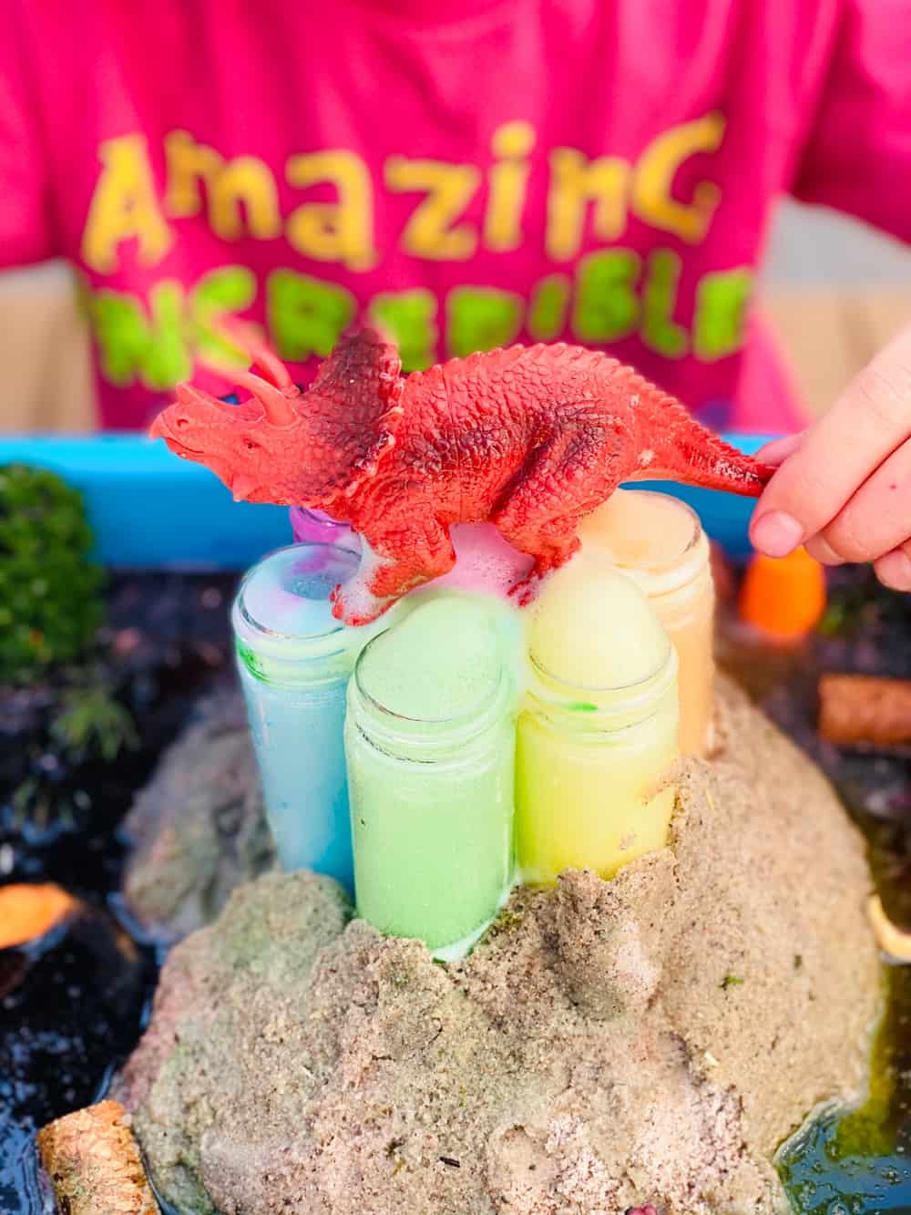 rainbow baking soda volcano science experiment for kids with toy dinosaur on top