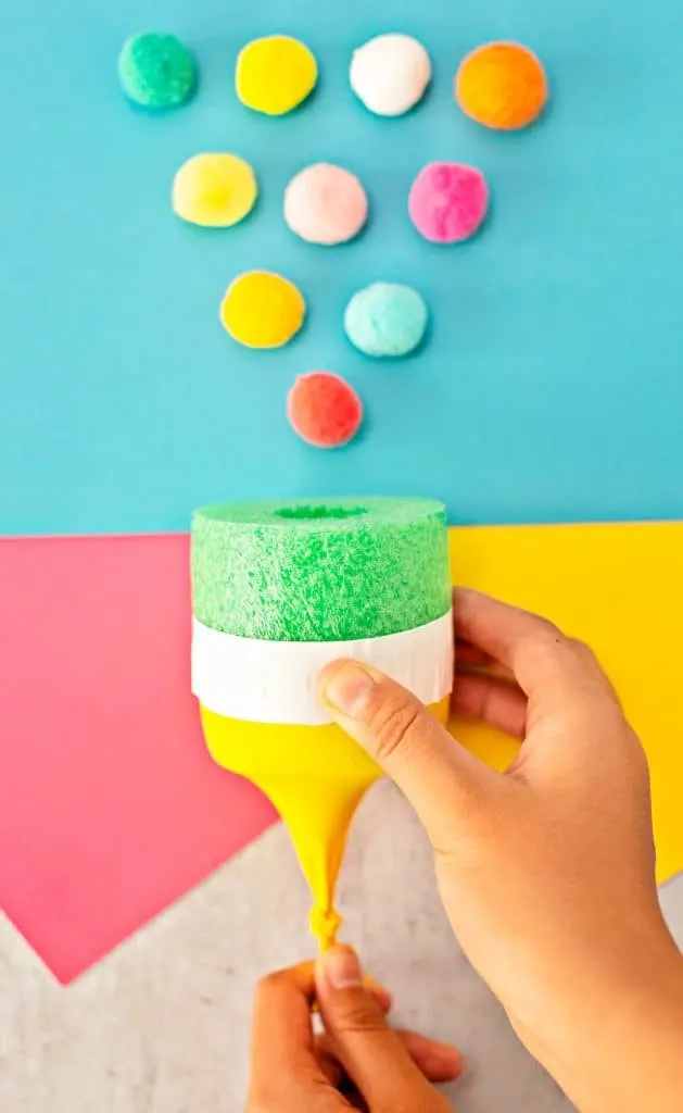 hand stretching balloon on a pom pom shooter