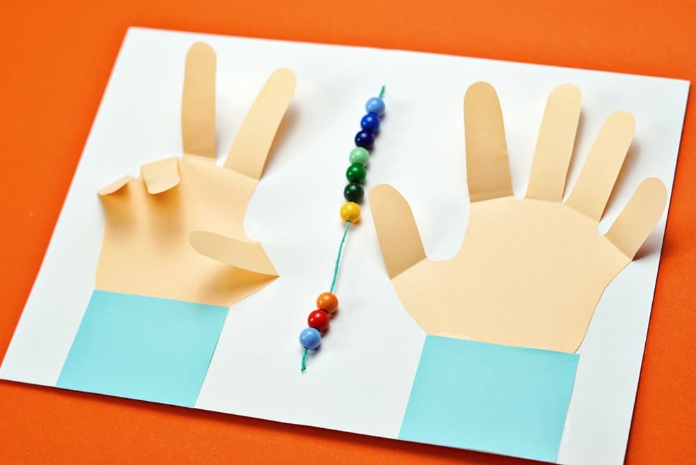 early math learning with paper hands cut out and counting beads 