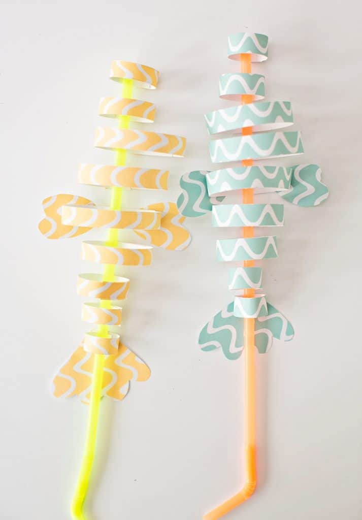 fish paper craft made from colorful strips of blue and orange paper and straws 
