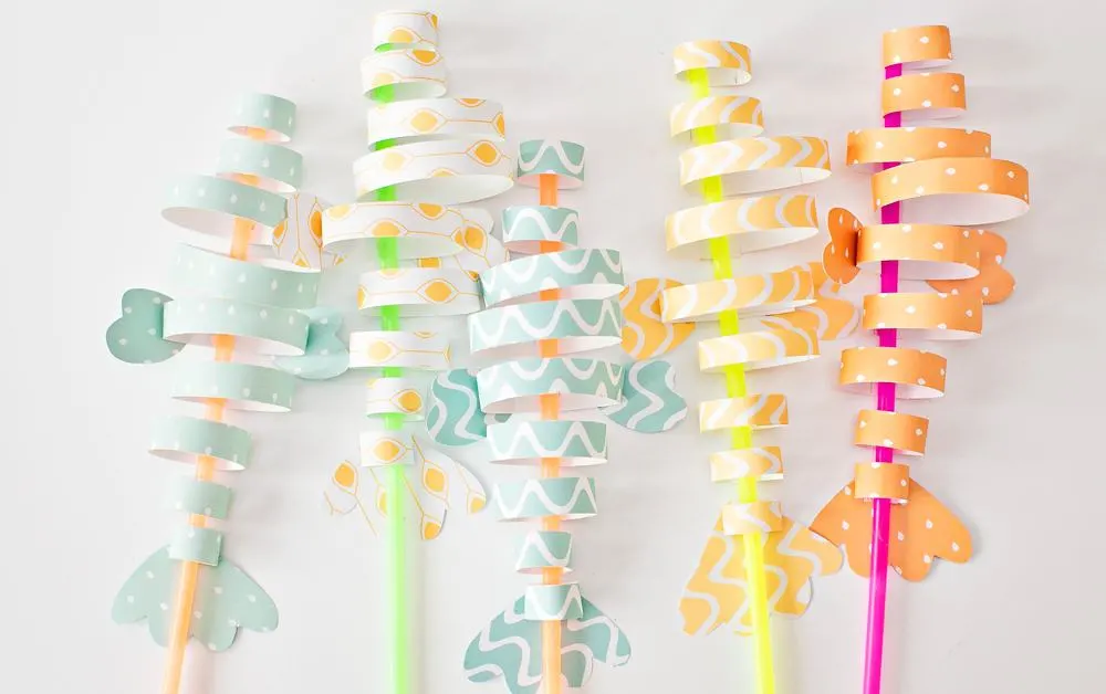 fish paper craft made from colorful strips of blue and yellow paper and straws 
