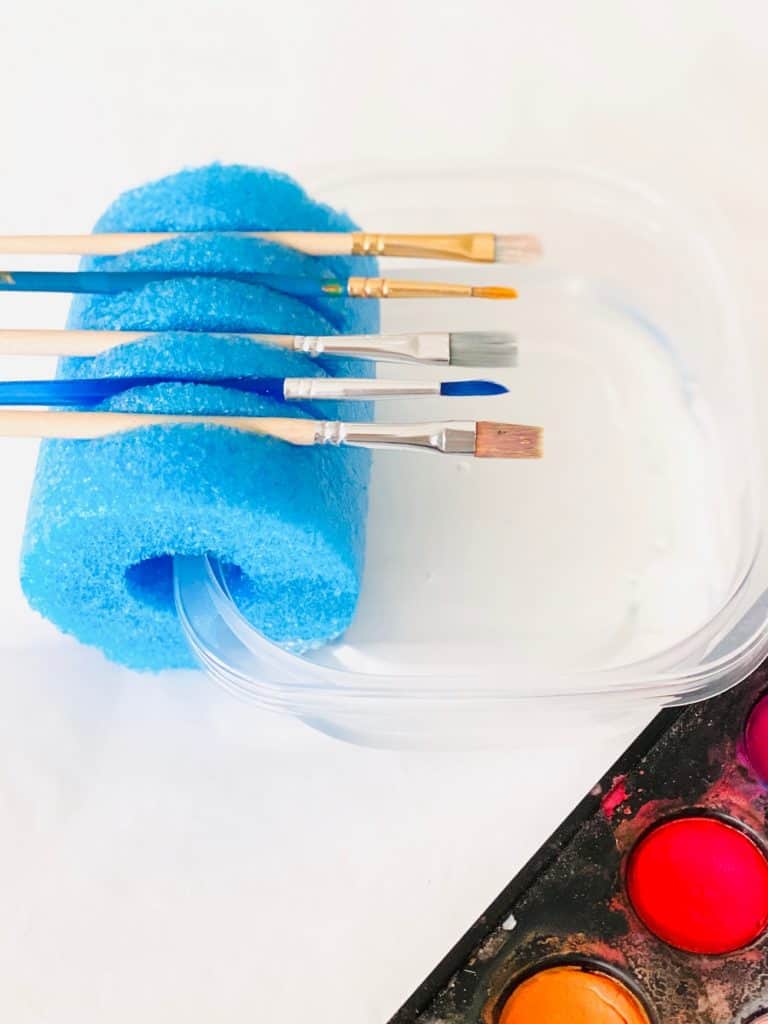 paint brushes held inside a pool noodle 