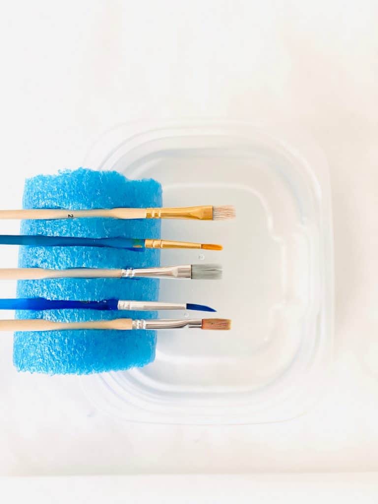 paint brushes held inside a pool noodle 